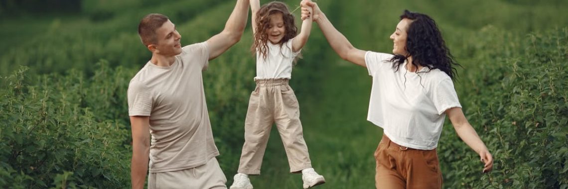 Joyful family moment in a green field during summer, capturing love and playfulness.